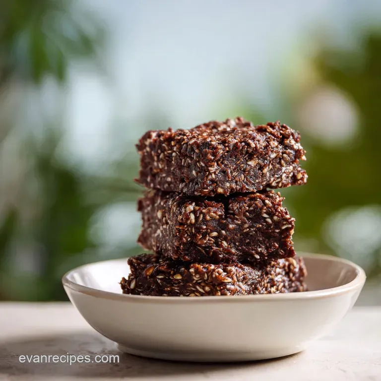 Sleek dark chocolate squares arranged on a white platter, garnished with fresh raspberries and a mint leaf.