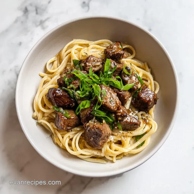 Swirled pasta topped with sliced medium-rare steak and a dusting of parmesan on a clean white ceramic plate.